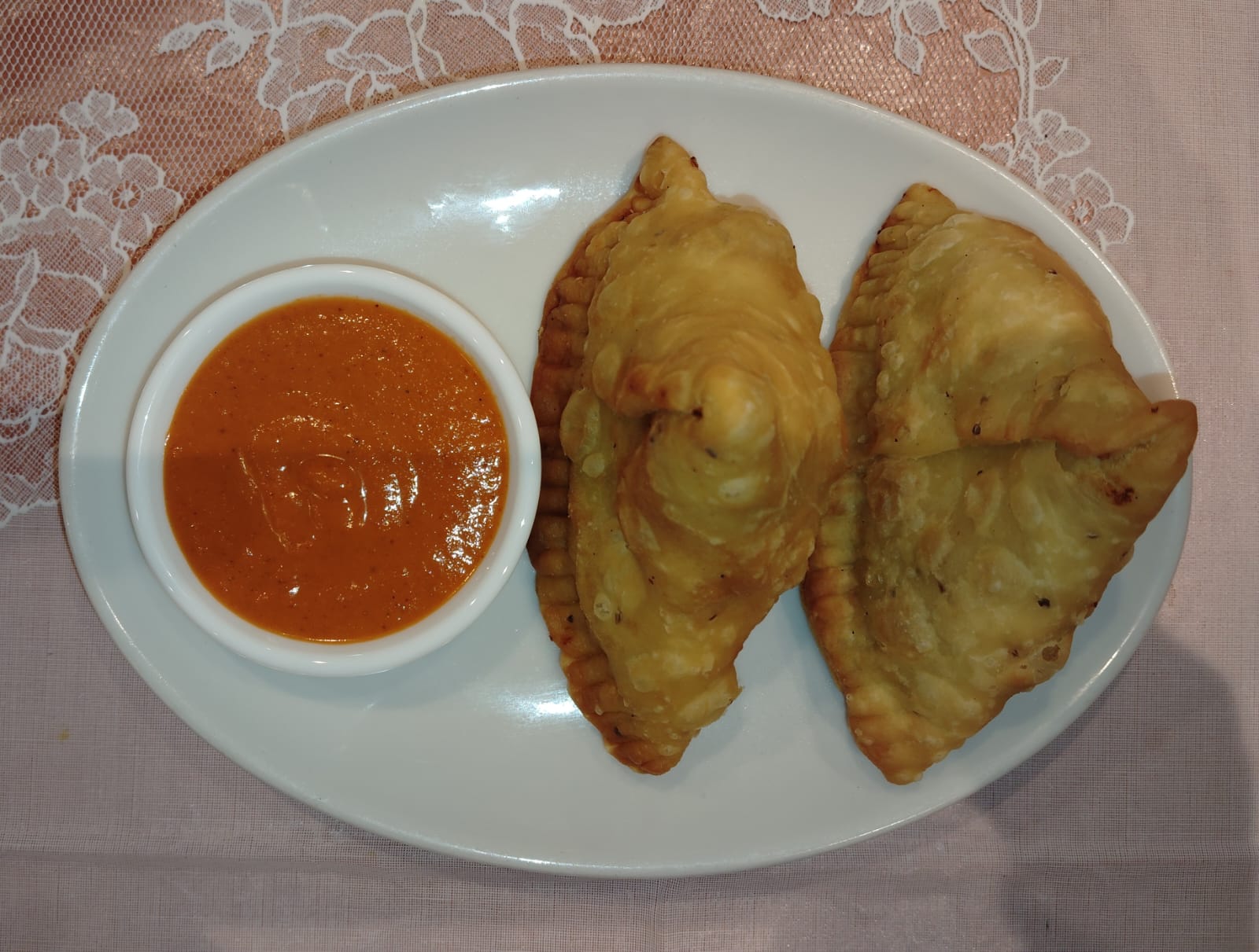 Two samosas with dipping sauce